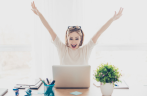 woman at desk with laptop celebrating her productivity