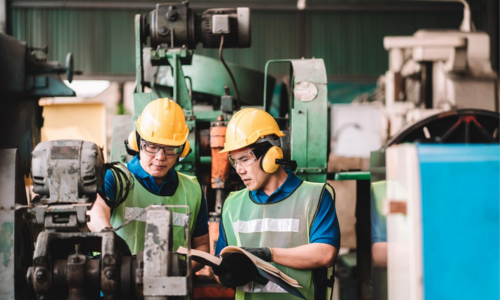 Factory Workers Operating Heavy Machinery Wearing hard hart and Noise-Cancelling Headphones